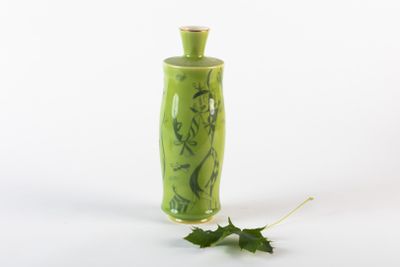 un vase vert orné d'une feuille sur le côté