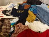 a pile of clothes that is sitting on a bed