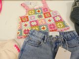 a crocheted top, jeans, and a pair of shoes on a table