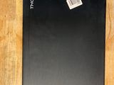 a black laptop on a wooden table with a sticker on it