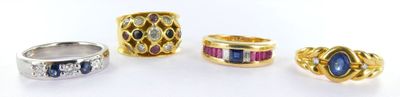 four different rings with different colored stones on a white surface
