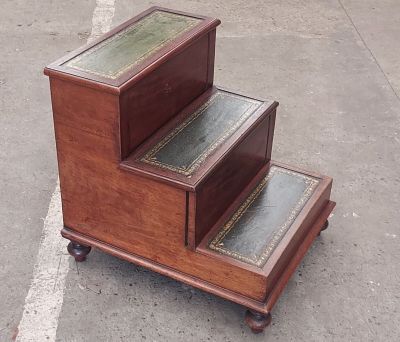 a wooden step stool with a glass top on wheels