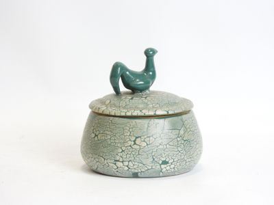 a green bird sitting on top of a cracky container