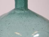 a green glass bottle with a black handle on a table