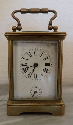 a small brass clock with roman numerals on the face