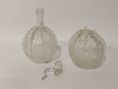 pair of clear glass vases on a white surface with a bottle in the background
