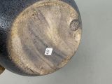a hand holding a black and white vase on a table
