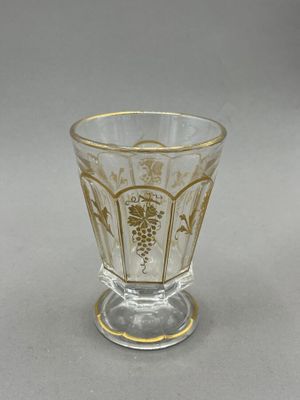 a glass cup with a gold decoration on it