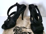 une paire de sandales noires à talons hauts posée sur un sac