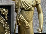 a gold statue of a man holding a flag and a clock