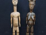 deux figurines en bois représentant un homme et une femme debout l'un à côté de l'autre