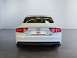 the rear end of a white audi sedan parked in a garage