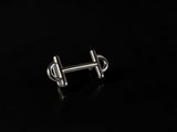 a close up of a pair of silver earrings on a black surface