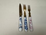 three forks and a knife sitting next to each other on a table