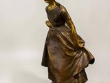 bronze statue of a girl with a basket on her head
