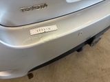 the rear end of a silver car with a sticker on it ' s bumper