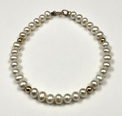 a close up of a white pearl necklace on a white surface