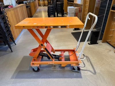 une petite table orange munie d'une poignée, dans un magasin