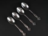 four silver spoons on a black surface with a black background