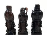 three black figurines of men with hats and canes