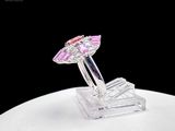 a pink and white diamond ring on a clear stand