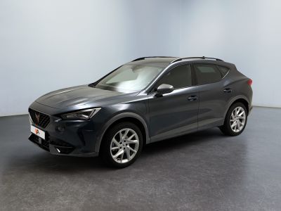 Une voiture grise est garée dans une pièce au sol noir.