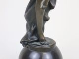 bronze statue of a woman holding a fan on top of a black base