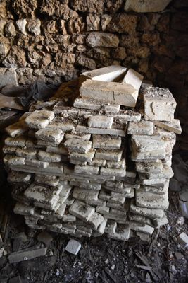 a pile of bricks sitting on the ground next to a stone wall