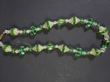 a close up of a green and white beaded necklace on a black surface