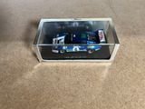 un camion miniature dans une boîte transparente posée par terre