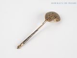 a gold spoon with a handle on a white surface