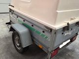 une petite remorque avec une caisse blanche à l'arrière