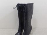 une paire de bottes noires posées sur un sol blanc