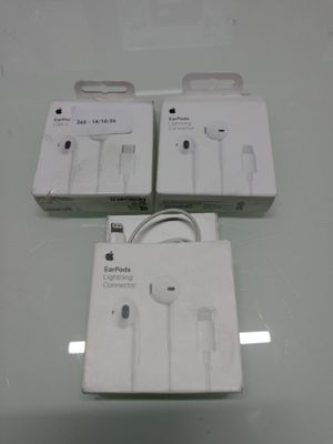 Trois écouteurs Apple EarPods sont posés sur une table en verre