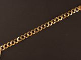 gros plan d'un bracelet en chaîne en or sur une surface noire