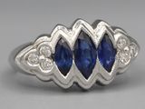 a close up of a blue sapphire and diamond ring on a gray surface