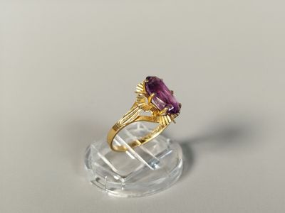 an image of a gold ring with a purple stone on top of a clear base