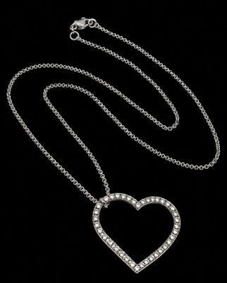 a diamond heart pendant on a chain on a black background