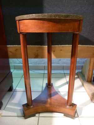 a small wooden table with a marble top on a tile floor