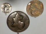 three metal medallions and a coin on a white surface