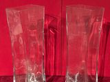 une paire de vases en verre transparent posés sur un fond de velours rouge