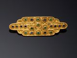 a close up of a gold broochle with green and blue stones