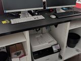 deux écrans d'ordinateur et une imprimante posés sur un bureau