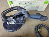 a close up of a corded sander on a floor with a box in the background