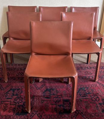 quatre fauteuils en cuir marron posés sur un tapis, au milieu d'une pièce recouverte de moquette