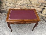 a small wooden table with a red leather top