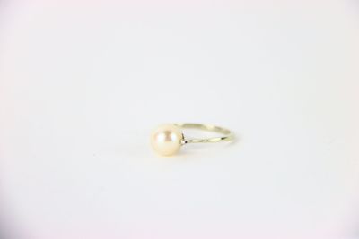 une bague en perle blanche posée sur une surface blanche