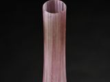 purple glass vase on a black surface with a black background