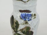 a white vase with a blue flower on it