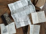 many old books on the floor with maps on them